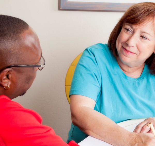 A female occupational therapist speaks with her male client.